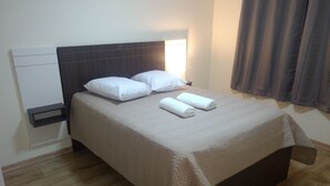 A neatly made bed with white linens, a bedside table, and a headboard. - CORREA PEREIRA RESIDENTIAL APARTMENT 3, sleeps up to 11 people, 3 bedrooms (CANELA)