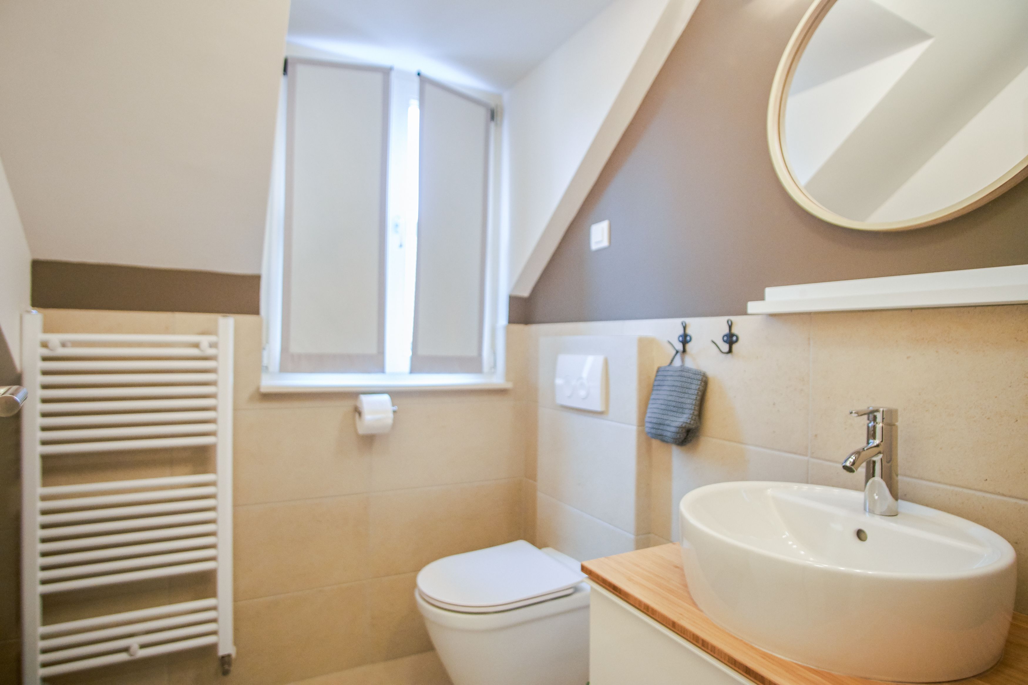 Ein Badezimmer mit Toilette, Waschbecken, Handtuchhalter und einem Fenster.