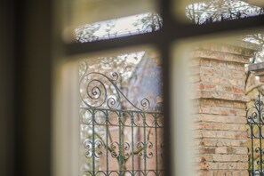 A close-up of a wrought iron gate with intricate designs, set against a brick wall. - Peacock Boutique Apartments (Zagreb)