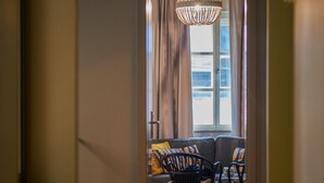 A hallway leading to a living area with a sofa and chairs, a chandelier, and a window with curtains. - Peacock Boutique Apartments (Zagreb)