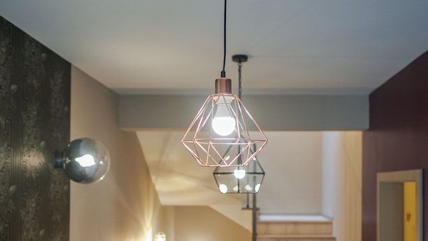 A staircase with a wooden finish and a wall-mounted light fixture above it. - Peacock Boutique Apartments (Zagreb)