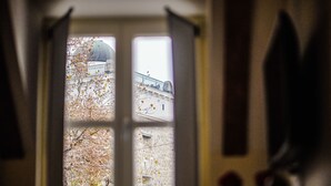 A view through a window with a stone wall and a building with a dome in the background. - Peacock Boutique Apartments (Zagreb)