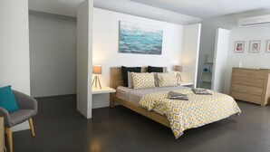 Un dormitorio moderno con cama, lámparas de noche, cómoda y un cuadro en la pared.