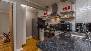 Una cocina moderna con electrodomésticos de acero inoxidable, encimera de granito y suelo de madera.