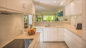 A modern kitchen with white cabinets, a dishwasher, and a fruit bowl on the counter. - Port Douglas Mirage Villa 123 (Port Douglas)