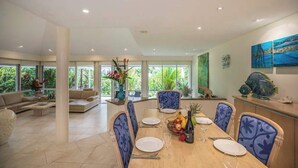 A spacious dining area with a wooden table set for four, surrounded by blue patterned chairs. - Port Douglas Mirage Villa 123 (Port Douglas)