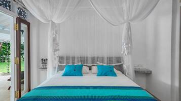 A bed with a white canopy, two blue pillows, and a teal and green striped bedspread.