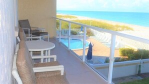 A balcony with a pool, beach view, and outdoor seating. - Beachcomber unit 204 (Longboat Key)