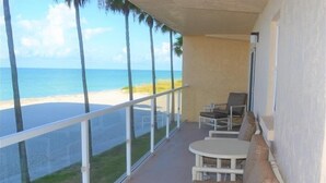A balcony with a view of the beach and ocean. There are chairs and a table. - Beachcomber unit 204 (Longboat Key)