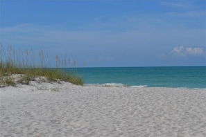 A beach with white sand and clear blue water.
