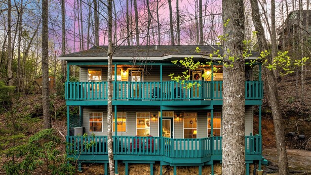 A two-story building with a balcony, surrounded by trees.
