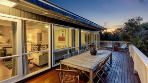 Une maison moderne dotée d’une terrasse, de grandes fenêtres et d’un coin repas.