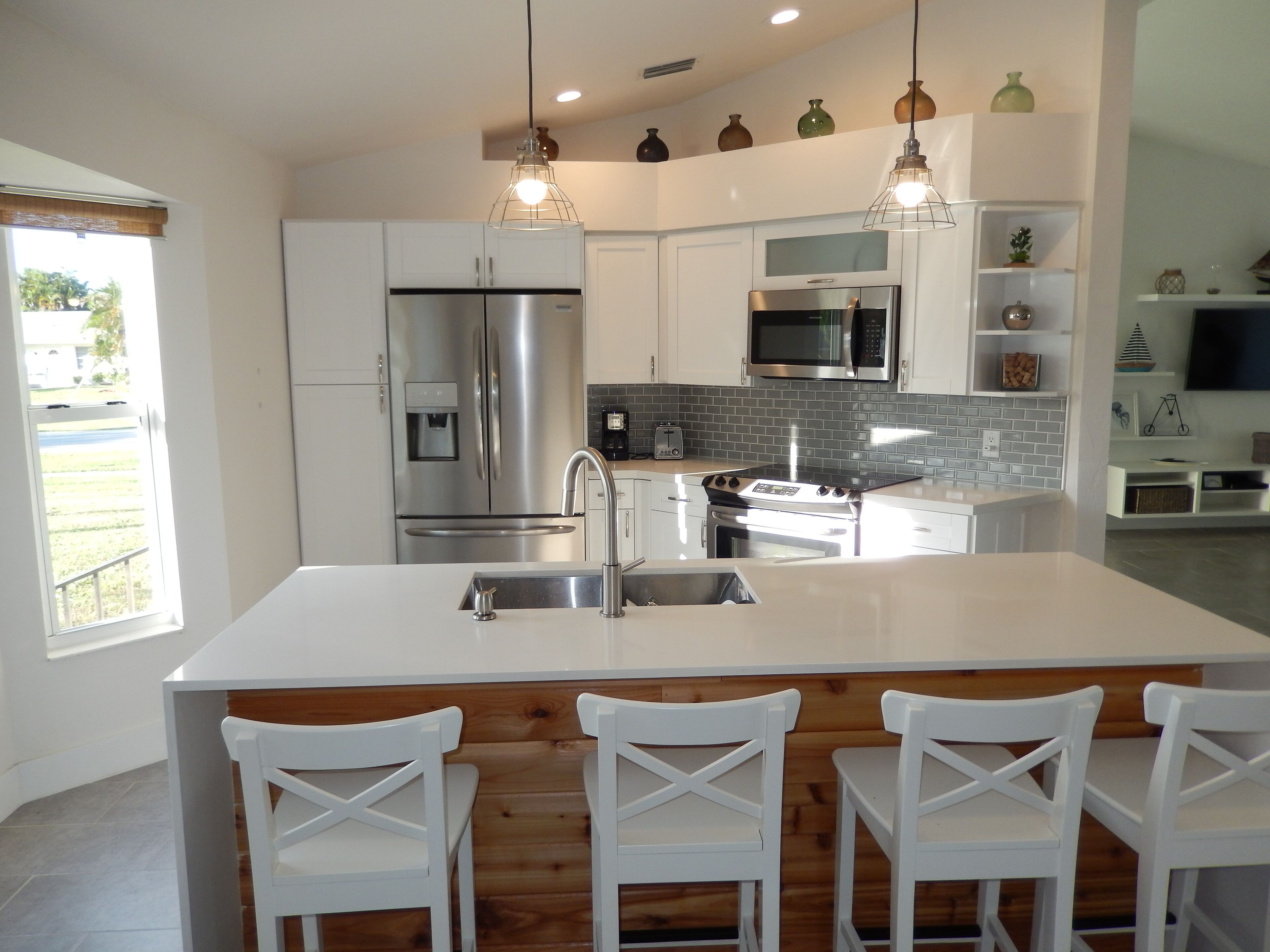 A modern kitchen with stainless steel appliances, a central island with bar stools, and a breakfast bar.