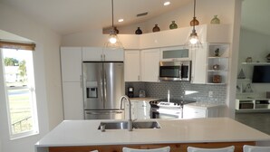 A modern kitchen with stainless steel appliances, a central island with bar stools, and a breakfast bar. - Beautiful house and great neighborhood! (Marco Island)