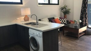 Eine kompakte Küche mit Einbauwaschmaschine, Spüle und einer kleinen Essecke mit Tisch und Stühlen.