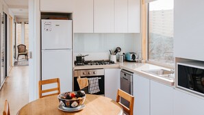 Une cuisine moderne avec des meubles blancs, une cuisinière, un évier et un coin repas comprenant une table et des chaises.