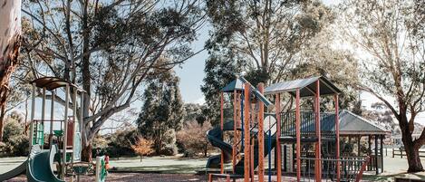 Ein Spielplatz mit Rutsche, Klettergerüsten und einer Laube.