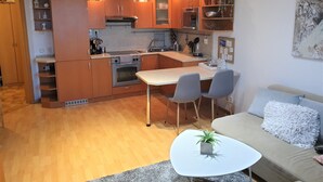 Ett kompakt kök med träskåp, en inbyggd ugn och en matplats med ett litet bord och stolar.