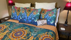 A bed with colorful, patterned bedding and two lamps on either side.