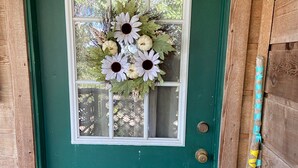 A green door with a window, a wreath, and a wooden door frame.