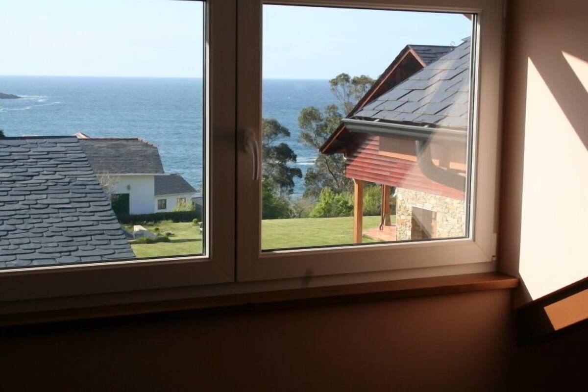A window with a view of the ocean and neighboring houses.