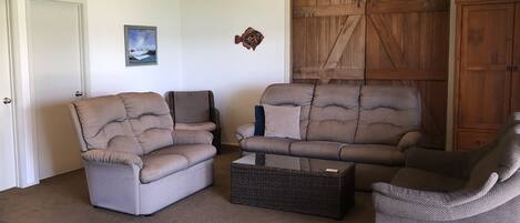 A living room with two grey sofas, a wicker coffee table, and a wooden barn door.