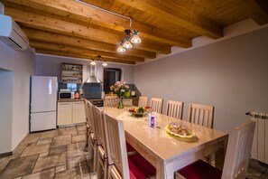 A kitchen with wooden ceiling beams, a dining table with chairs, and a refrigerator. - LUXURY VILLA ON SPACIOUS PRIVATE PROPERTY  (Rakalj)