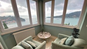 Une chambre d’angle avec vue sur la mer, deux fauteuils, une petite table ronde et un radiateur.