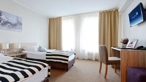 A hotel room with two beds, a desk with a computer, a chair, and a TV mounted on the wall. - Hotel Port 110 (Ilawa)