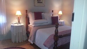 A bedroom with a bed, two bedside tables with lamps, a wooden headboard, and a framed picture on the wall. - ROSE AT LEAFIELD COTTAGES (Dixons Creek)