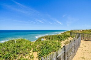 Una spiaggia con una recinzione di legno e vegetazione che conduce verso l'oceano.