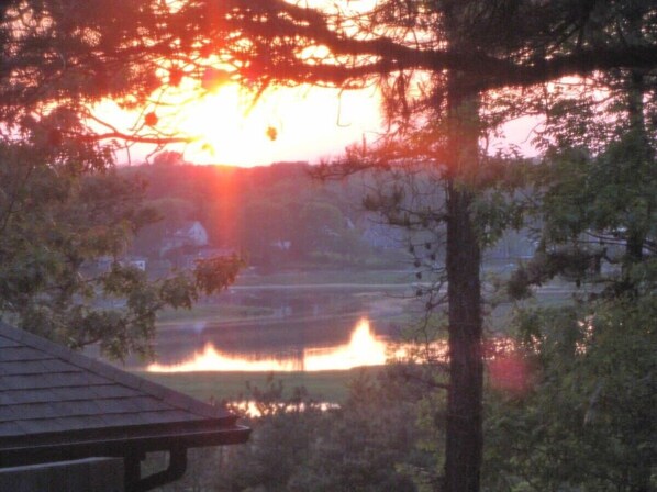 A sunset over a calm lake with trees framing the view. - On the bay in Wellfleet - walk to water! (Wellfleet)
