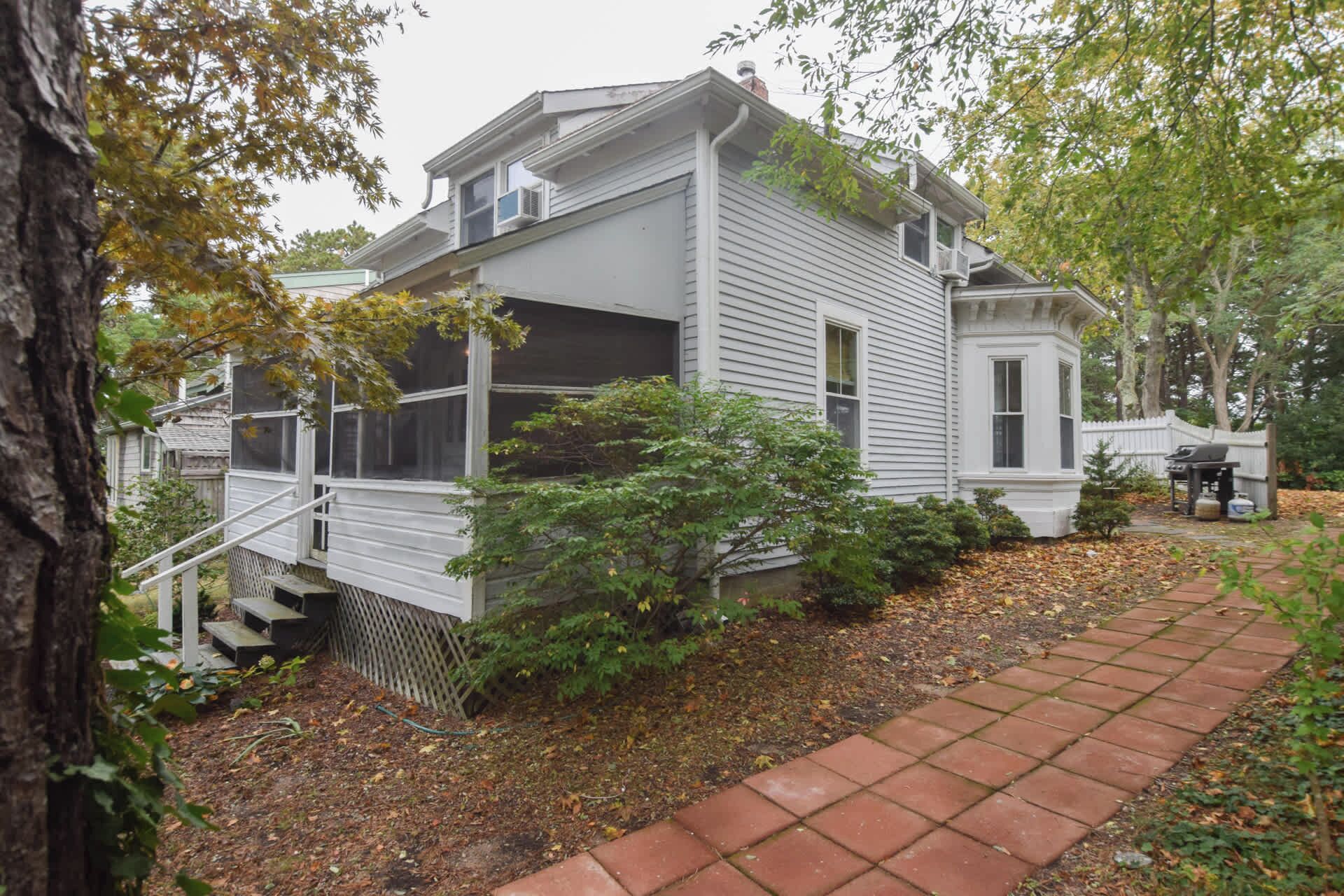 A two-story house with a covered porch and a brick pathway leading to the front door.