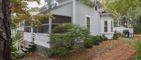 A two-story house with a covered porch and a brick pathway leading to the front door.