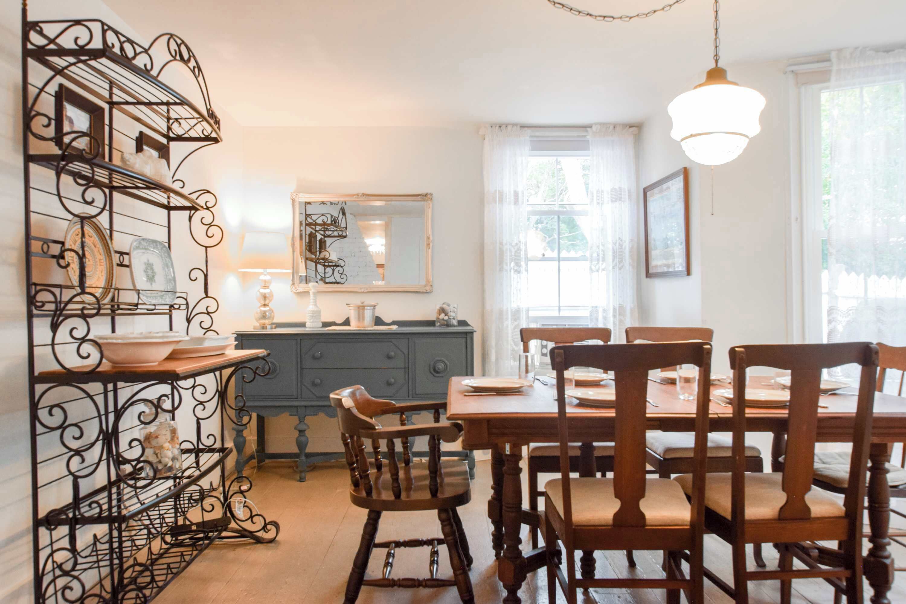 A dining area with a wooden table and chairs, a blue cabinet, and a decorative metal shelf.