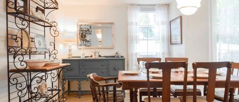 A dining area with a wooden table and chairs, a blue cabinet, and a decorative metal shelf.