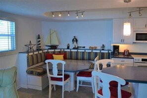 A modern kitchen with white cabinets, a built-in microwave, and a large island with seating.
