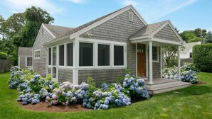 A two-story house with a covered porch and a front yard with hydrangea bushes. - 1 min drive to Rock Harbor, 2 min to Town! (Orleans)