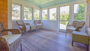 A covered porch with wicker furniture and large windows. - 1 min drive to Rock Harbor, 2 min to Town! (Orleans)
