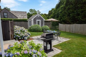 Enjoy al fresco dining and relaxation in this serene backyard patio, complete with a barbecue grill and comfortable seating.