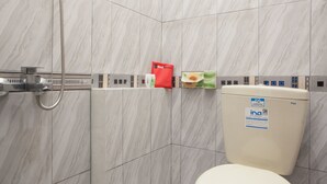 A bathroom with a toilet, a shower, and a hand dryer. There are toiletries on the wall. - RedDoorz near Banyuwangi Baru Station (Banyuwangi)