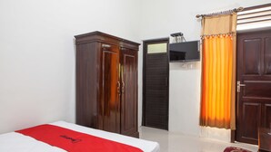 A hotel room with a bed, wardrobe, and a television. - RedDoorz near Banyuwangi Baru Station (Banyuwangi)