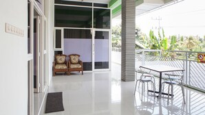 A clean, modern room with a balcony, a dining table with chairs, and a sofa. - RedDoorz near Banyuwangi Baru Station (Banyuwangi)