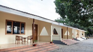 Una hilera de edificios de una sola planta con tejado de tejas, puertas de madera y un área de entrada pavimentada con escalones.