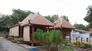 Un edificio tradicional con tejado de tejas y estructura de madera, rodeado por un jardín con diversas plantas y un camino empedrado.