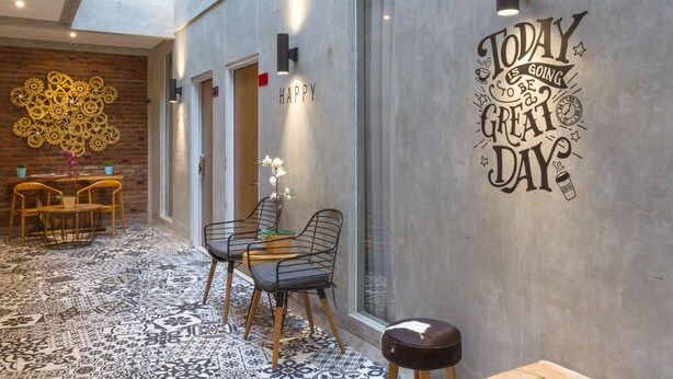 Un intérieur moderne avec un espace salon comprenant une table et des chaises, un mur décoratif orné d’une citation inspirante et un sol à motifs.