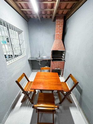 Una pequeña cocina con un horno de ladrillo, un lavamanos y una ventana con barrotes.