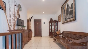 Un pasillo con un banco de madera, un televisor y una puerta.