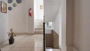 Un interior limpio y moderno con suelo de baldosas, una planta en maceta y un extintor en la pared.
