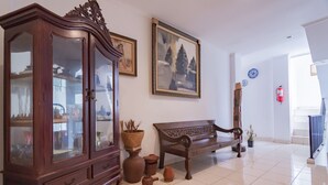 Una habitación amplia con un armario de madera, un banco y un cuadro en la pared.